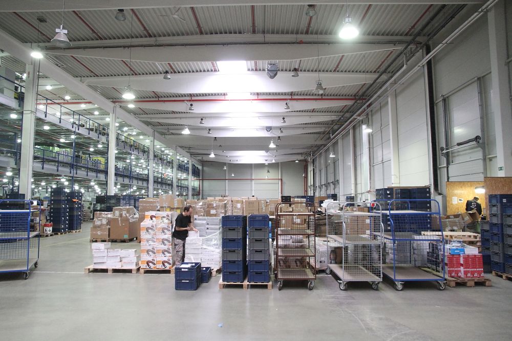 Tudy přichází do skladu nové zboží. Zaměstnanci ho vybalí, načtou do systému a připraví k přesunu na místo, kde bude uskladněno.