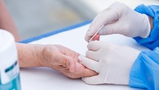 Detail rukou při testování z kapky krve z prstu