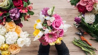 Floristka drží v rukou barevnou kytici z růží a gerber