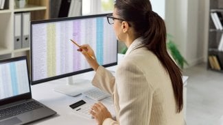 Žena v kanceláři pracuje na počítači, kde má spoustu tabulek