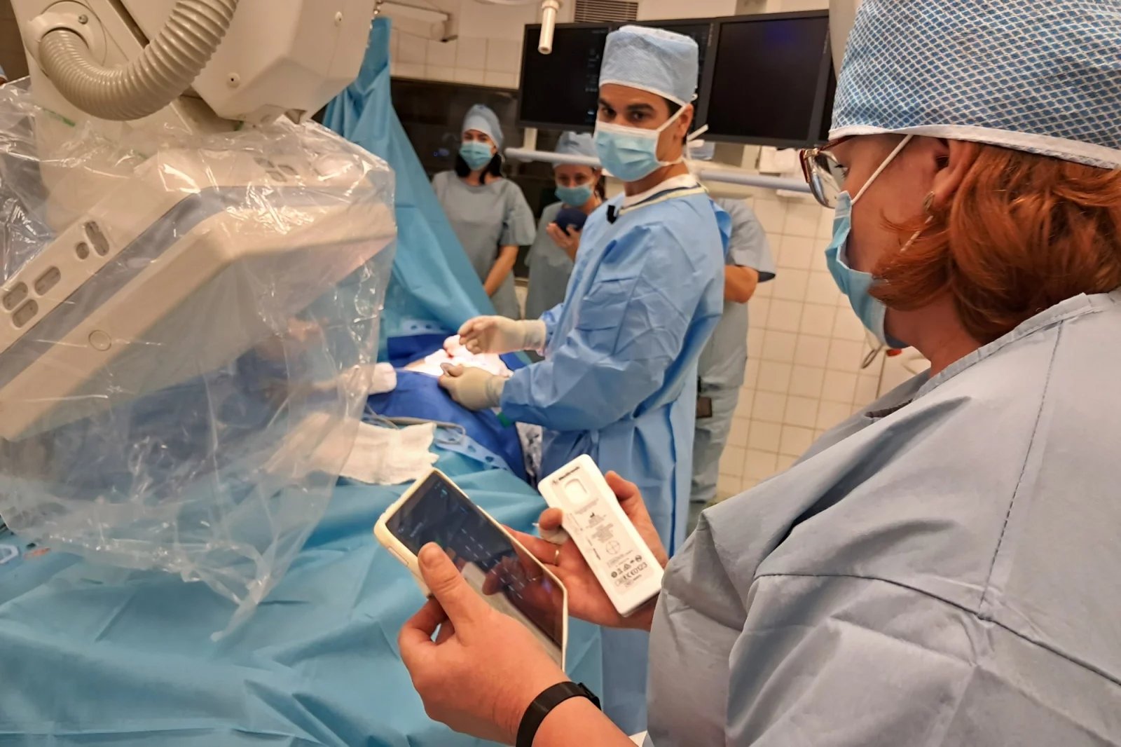 Podstatnou část zákroku tvoří zkouška a vyladění přístroje. Lékař to dělá ve spolupráci s vyškolenou sestrou. K dispozici mají nemocniční tablet a pacientský ovladač (na snímku bílá krabička v pravé ruce zdravotní sestry).