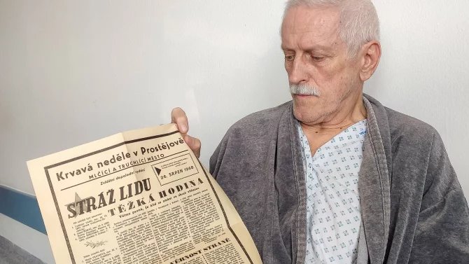Starší muž s výtiskem novin z roku 1968