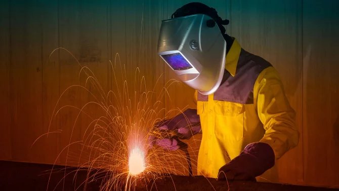 Muž ve svařovací masce tvoří jiskry při svařování
