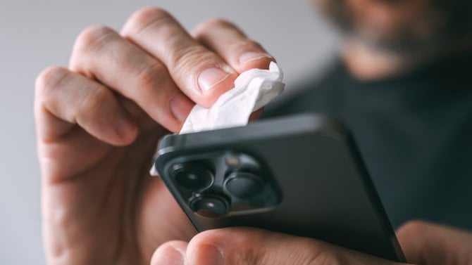 Muž čistí displej smartphonu