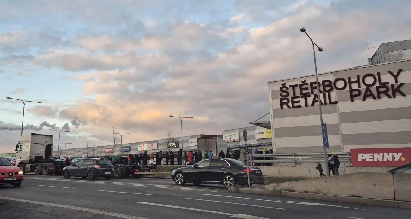 Za auty je vidět fronta lidí stojících na vstup do Lidl Outletu (druhý den otevření 16:30 h)