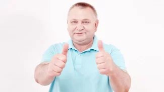 Starší muž v bílém tričku stojí a ukazuje palce nahoru