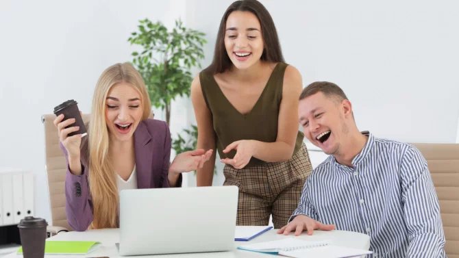 Lidé smějící se v kanceláři u počítače