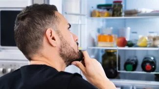 Mladý muž nahlíží do lednice, jakoby něco hledal