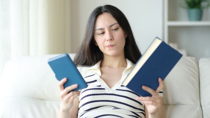 Žena, která se rozhoduje mezi dvěma knihami, které drží v ruce.