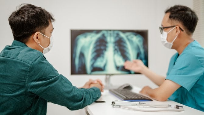 Lékař pacientovi ukazuje na rtg snímku, jak vypadá rakovina plic