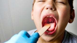 Lékař se dívá do krku školáka