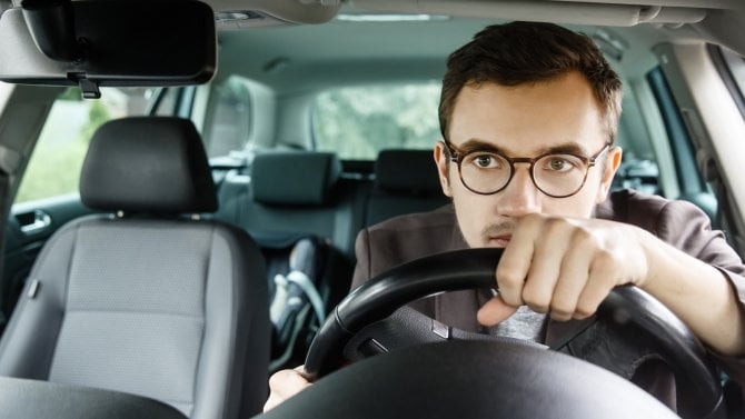 Muž s brýlemi řídí auto