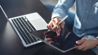 Mladá podnikatelka sedící na podlaze a používající stylus a digitální tablet, pracující na přenosném počítači v domácí kanceláři. Studentka studující online, e-learning