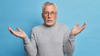 Starší muž stojí s rozpřaženýma rukama a tváří se, jako by něčemu nerozuměl