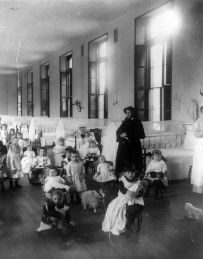 Sestra Irene z New York Foundling Hospital s dětmi. Sestra Irene patří k průkopnicím moderní adopce.