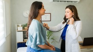 Lékařka vyšetřuje mladou pacientku v ordinaci stetoskopem