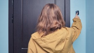 Žena stojí u vstupních dveří a zvoní na zvonek.