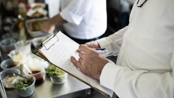 Inspektor kontroluje přípravu jídla v restauraci