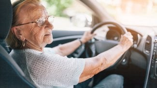 Seniorka sedí za volantem a řídí vůz