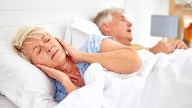 Muž chrápe a žena si zakrývá uši polštářem