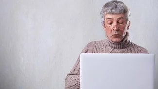 Muž sedí za počítačem s vážnou tváří a pracuje