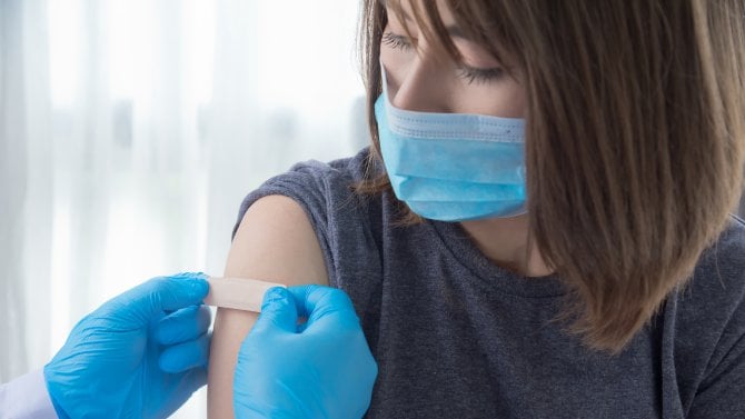 Lékaři lepí náplast na paži očkované ženy