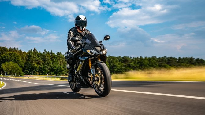 Motorkář jedoucí po silnici vedle pole