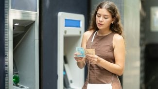 Znechucená žena při výběru peněz v bankomatu