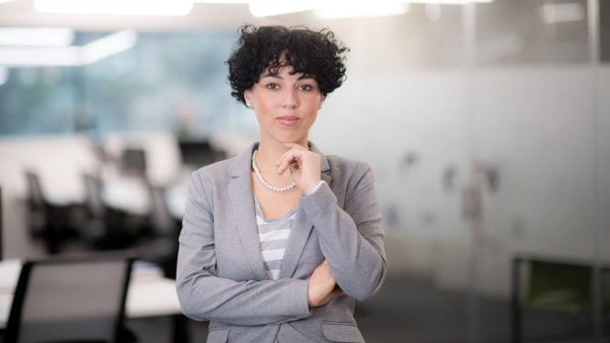 Hezká žena stojící v kanceláři se zamyšleným výrazem