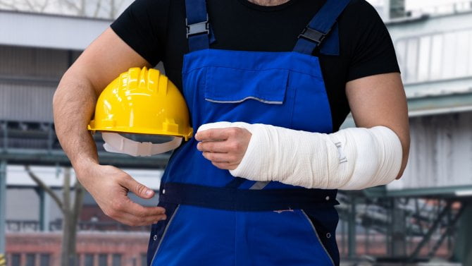 Pracovník v montérkách se zlomenou rukou