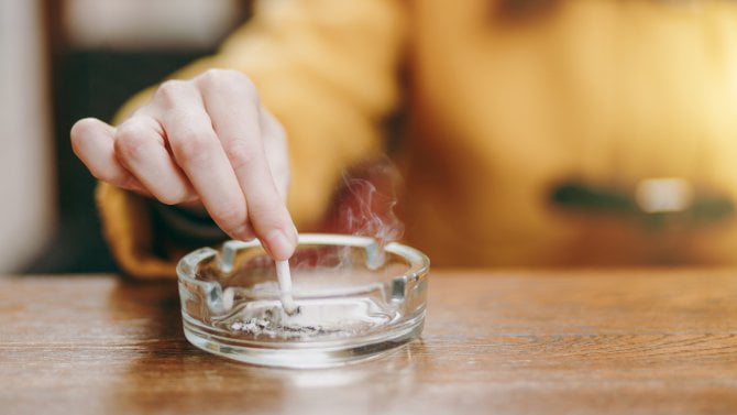 Detail ruky, jak típe cigaretu do popelníku