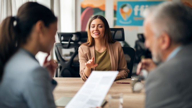 Úřednice v kanceláři u stolu s dokumenty a klienty