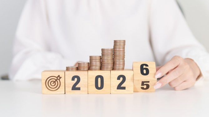 Čtyři rostoucí hromádky mincí a rok 2026 z kostek.