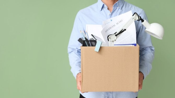 Vyhozený muž drží krabici s osobními věcmi na zeleném pozadí s prostorem pro text