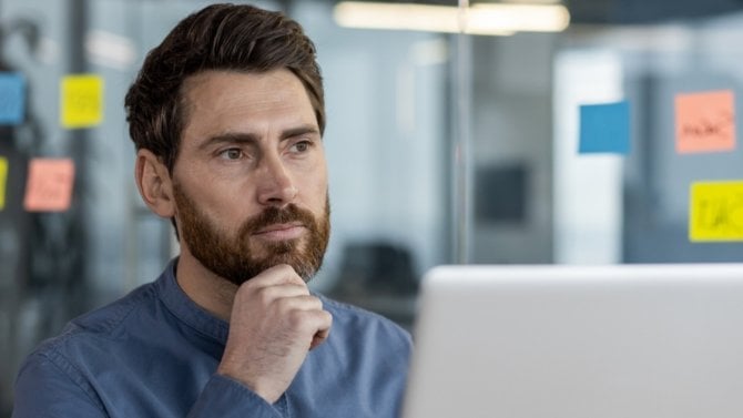 Muž sedící v kanceláři u počítače a přemýšlející