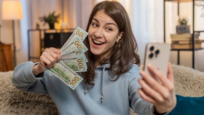 Mladá žena se natáčí s penězi v ruce