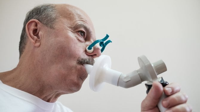Starší muž fouká do spirometru