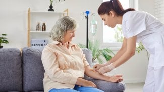 Sestra podává ženě v domácím prostředí infuzi