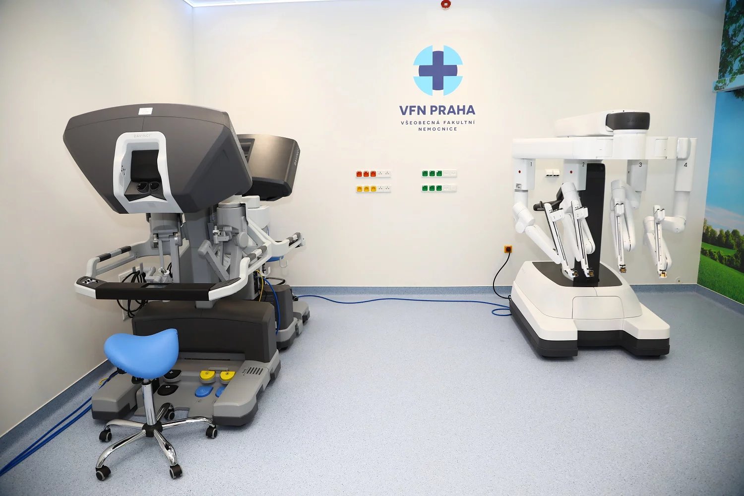 Ve VFN mají k robotovi dvě konzole (vlevo). Vpravo od nich stojí sloup se čtyřmi rameny, které jsou prodlouženýma rukama chirurga.