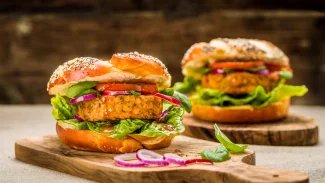 Dva vegetariánské hamburgery na dřevěném prkénku.
