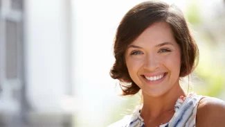 Usměvavá žena na rozmazaném pozadí.