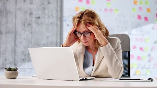 Starší žena v kanceláři čelí šokující informaci
