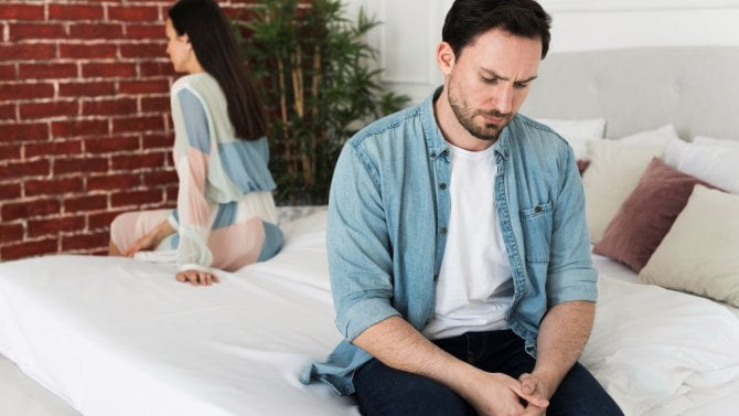 Frustrovaný muž a zklamaná žena sedí na posteli
