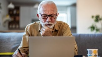 Senior sedí u počítače a přemýšlí