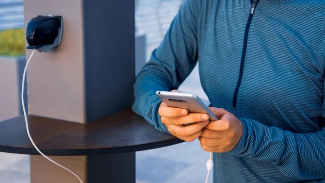Muž nabíjející telefon na veřejném místě