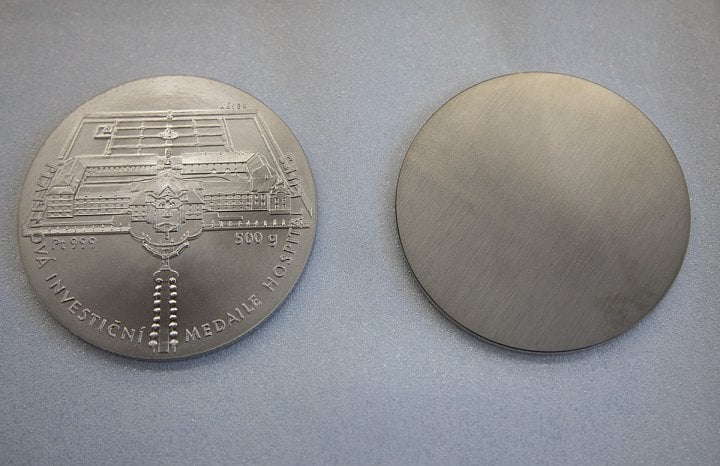 Vyražená medaile a polotovar (střížek), ze kterého se medaile razí