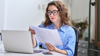 Mladá žena sedící v kanceláři studuje papírový dokument