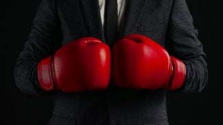 Muž v obleku s červenými boxerskými rukavicemi.