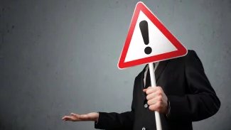 Muž s dopravní značkou, na které je vykřičník