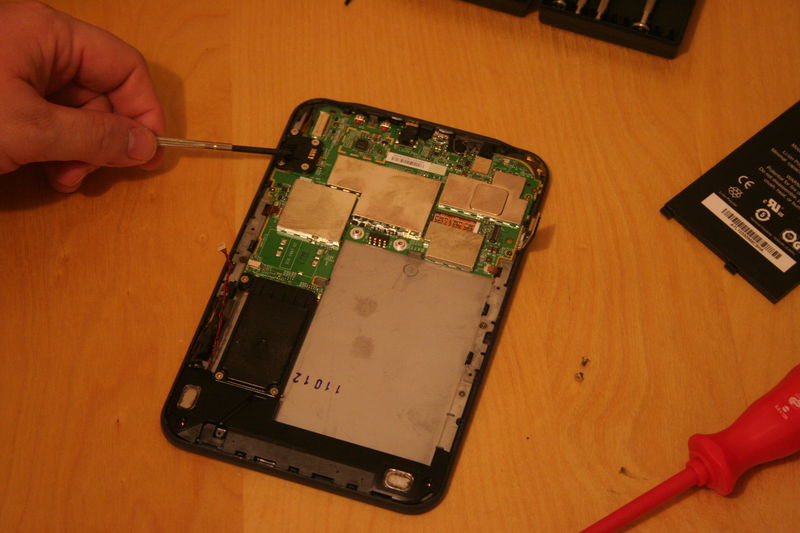 Povolte čtyři šroubky držící malý plastový propojovací díl. Ten sundejte. Poté povolte jedenáct malých šroubků rozmístěných po celé desce a desku sundejte.